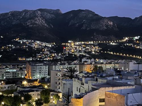 a city lit up at night with mountains in the background at Casa Marwan in Tetouan