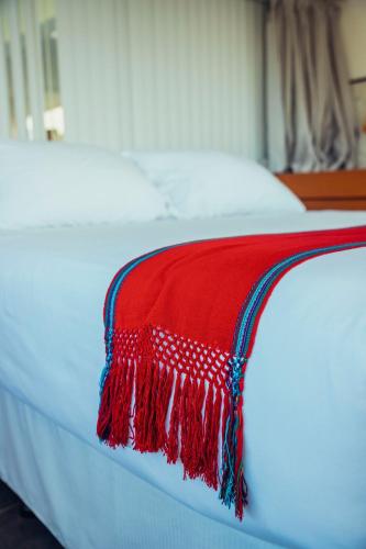 a red blanket on the edge of a white bed at El Dragon Hotel in San Marcos La Laguna