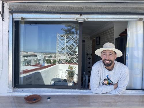 a man wearing a hat looking out of a window at Casa Marwan in Tetouan