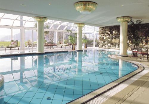 ein großer Pool in einem Hotel mit Säulen und Fenstern in der Unterkunft Aghadoe Heights Hotel & Spa in Killarney