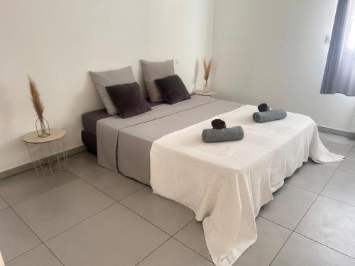 - 2 lits dans une chambre blanche avec 2 tables dans l'établissement Appartement Rocade, à Ajaccio