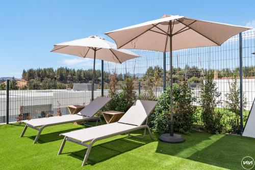 due sedie e un ombrellone in cima all'erba di ViVi Homes - Marisol Pool, Sauna, Gym, Spa & Beach a Mijas Costa