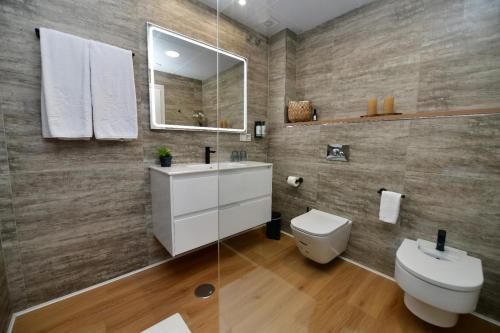 a bathroom with a toilet and a sink and a mirror at Hotel Salobreña Suites in Salobreña