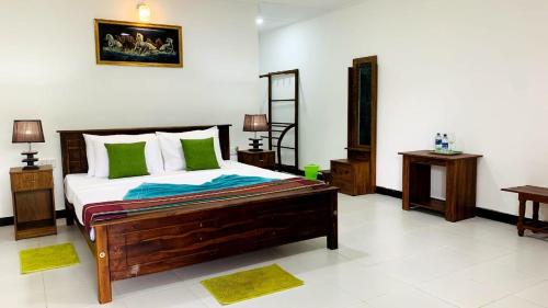 a bedroom with a large bed with green pillows at Sigiri Prabha Villa in Sigiriya
