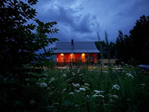 a house with lights on it in a field at Chatka nad Jeziorem Czostków JustChill in Czostków