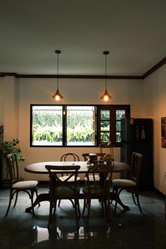 a dining room with a table and chairs and two windows at Dalang Nimman House大浪清迈宁曼路4卧4卫独栋别墅 in Chiang Mai