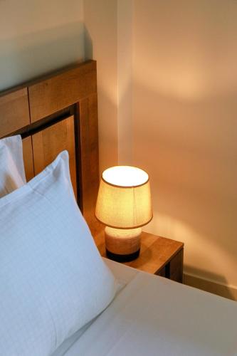 a lamp sitting on a table next to a bed at Feel Like home appartment in Xanthi