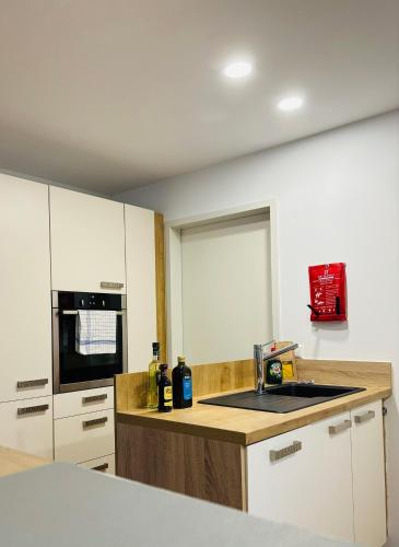 a kitchen with white cabinets and a counter top at REMA Homes - Jacuzzi Terrasse 55' TV Küche Regendusche in Bad Bellingen