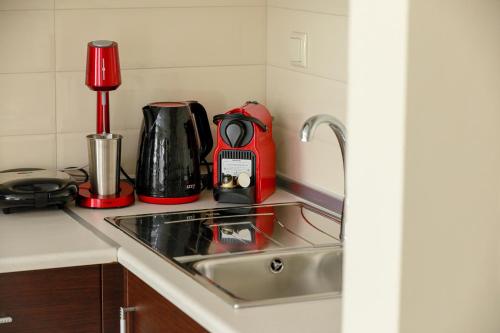 a kitchen counter with a sink and a red appliance at Feel Like home appartment in Xanthi