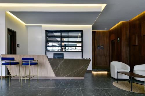 an office lobby with a wooden counter and blue chairs at Neo by Wynwood House in Bogotá