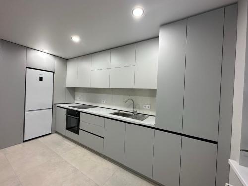 a kitchen with white cabinets and a sink and a refrigerator at Apartament nou in Căuşeni