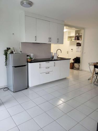  La cuisine est équipée de placards blancs et d'un réfrigérateur. dans l'établissement Confort Appart familial Paris, à Villejuif