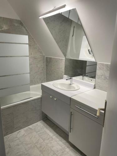 une salle de bain blanche avec un lavabo et un miroir dans l'établissement TM Appartement BASTILLE, à Paris