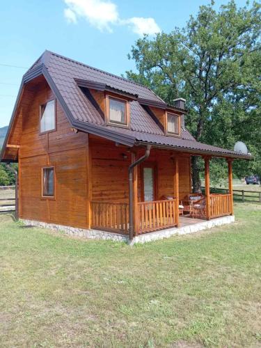 a large wooden cabin with a gambrel roof at Guest House Krsmanovic in Mokra Gora