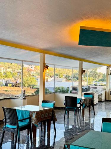 a restaurant with tables and chairs and large windows at Rose Hotel B&B in Patara