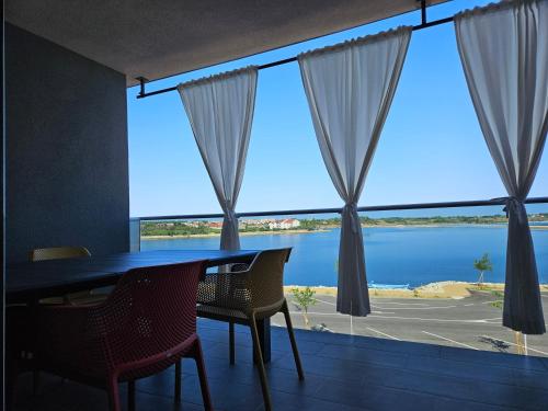 a dining room with a table and chairs and a large window at APARTMAN SUNSIDE2 NIN in Nin