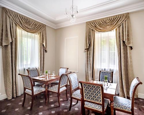 a dining room with a table and chairs and windows at Pałac Zegrzyński in Zegrze