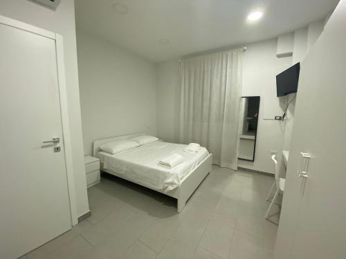 Un dormitorio blanco con una cama y un televisor. en B&B Loretta, en Marcianise