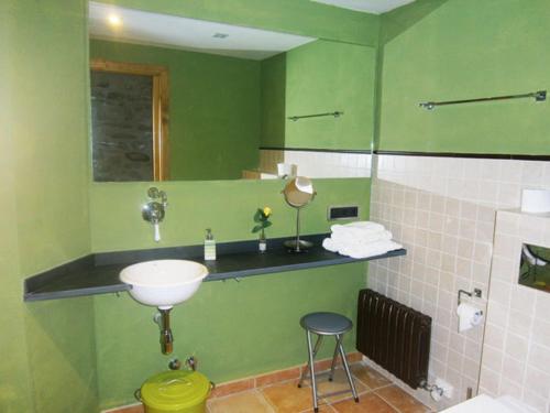 un bagno verde con lavandino e specchio di Casa Rural Cal Xico ad Adrall