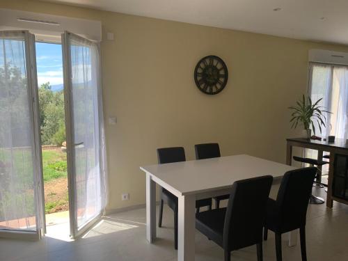 une salle à manger avec une table, des chaises et une horloge murale dans l'établissement Villa Bella, à La Gaude