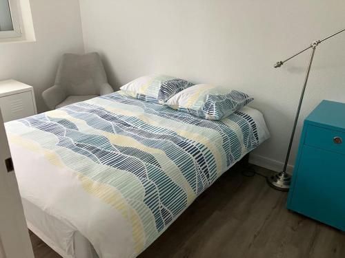 - un lit avec deux oreillers et une chaise dans une chambre dans l'établissement Spacieux Appartement Familial - 10 mnt du RER B, à Massy