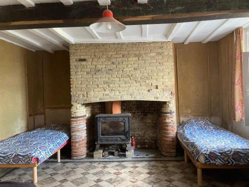 - un salon avec une cheminée et 2 lits dans l'établissement La fermette, à Herzeele