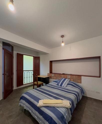 a bedroom with a bed with a desk and a window at Casa Huaca in Lima