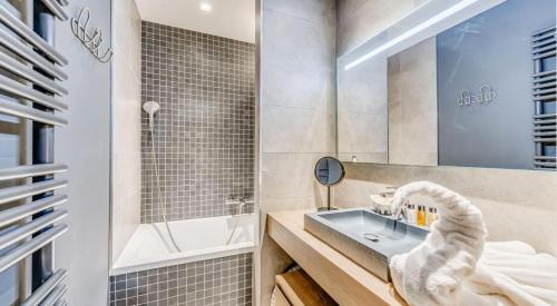 une salle de bain avec un lavabo, une baignoire et un miroir dans l'établissement Résidence Phoenix - 2 pièces cabine 5 personnes PREMIUM 3 MAE-2011, à Tignes