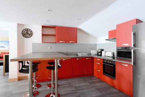 une cuisine avec des armoires rouges et un comptoir dans l'établissement Résidence Backgammon - LE BACKGAMMON MAE-3413, à Les Coches