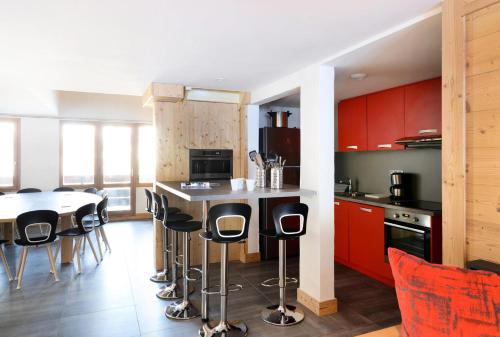 une cuisine avec des placards rouges et une table avec des tabourets dans l'établissement Résidence Backgammon - LE BACKGAMMON MAE-3414, à Les Coches