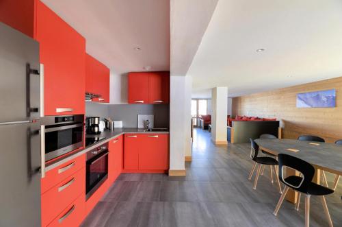 une cuisine avec des placards rouges et une table avec des chaises dans l'établissement Résidence Backgammon - LE BACKGAMMON MAE-3418, à Les Coches