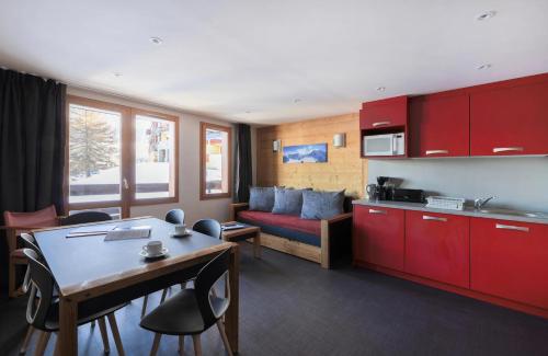 - une cuisine et un salon avec des armoires rouges et une table dans l'établissement Résidence Backgammon - LE BACKGAMMON MAE-3456, à Les Coches