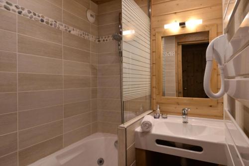une salle de bain avec un lavabo, une baignoire et un miroir dans l'établissement Résidence Onyx - 2 Pièces pour 5 Personnes 58, à Mâcot La Plagne