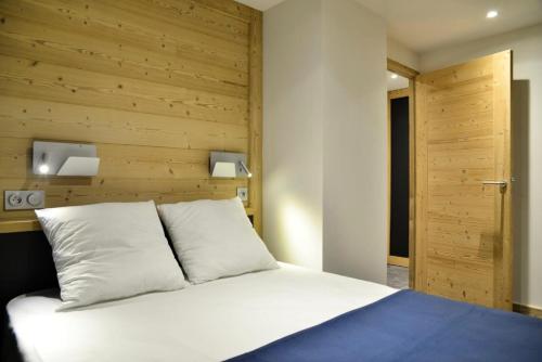 une chambre avec un lit blanc avec une tête de lit en bois dans l'établissement Résidence Backgammon - LE BACKGAMMON MAE-3462, à Les Coches