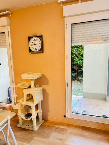 une horloge sur un mur à côté d'une fenêtre avec une échelle pour chat dans l'établissement Niti, à Cergy