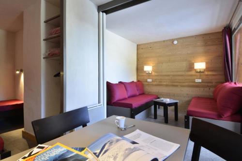 une pièce avec des chaises rouges et une table avec un livre dans l'établissement Residence 3000 - Studio pour 4 Personnes 34, à Mâcot La Plagne