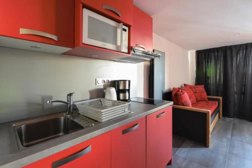 - une cuisine avec des placards rouges, un évier et un canapé dans l'établissement Résidence Backgammon - LE BACKGAMMON MAE-3555, à Les Coches