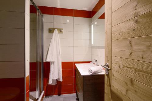 La salle de bains est pourvue d'un lavabo et d'une porte de douche en verre. dans l'établissement Résidence Backgammon - LE BACKGAMMON MAE-3556, à Les Coches