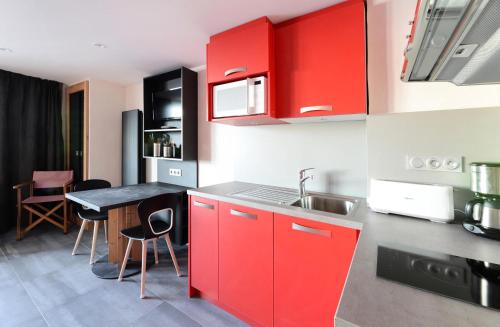 une cuisine avec des placards rouges et une table avec des chaises dans l'établissement Résidence Backgammon - LE BACKGAMMON MAE-3557, à Les Coches