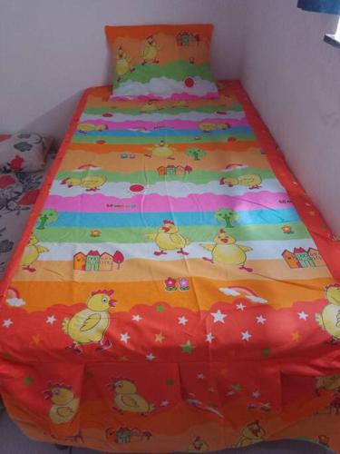 a bed with a colorful comforter with ducks on it at Casa Temporada em Barreirinhas in Barreirinhas