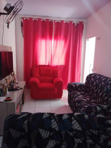 a living room with a red couch and pink curtains at Casa Temporada em Barreirinhas in Barreirinhas