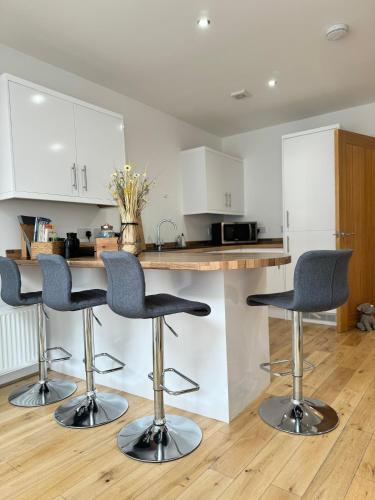 a kitchen with three bar stools in front of a counter at The Courtyard, 4 - Bed, Sleeps 6, Pets Welcome in Ulverston
