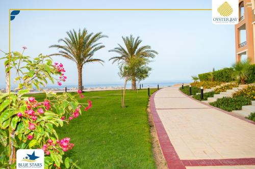a walkway near the beach with palm trees and flowers at Oyster bay Suite 01 in Abu Dabab
