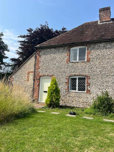 a brick house with a window and a bush in the yard at Wish End Cottage in Ratton Village