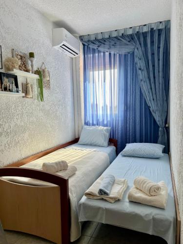 two beds in a room with blue curtains at Thea Holiday Home in Nea Potidaea
