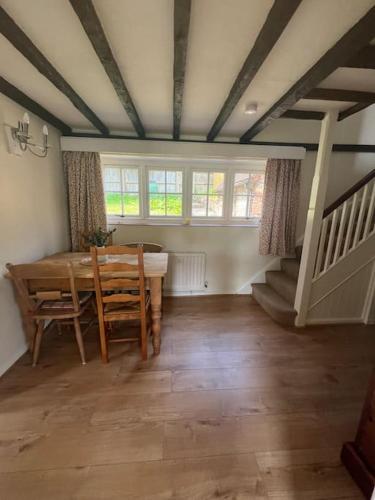 a dining room with a table and some windows at Wish End Cottage in Ratton Village