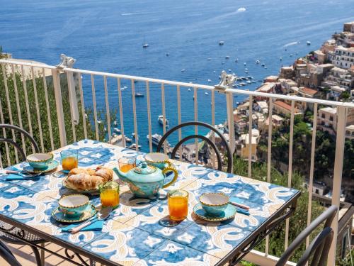 a table on a balcony with a view of the ocean at Casa Vittorina - De Vivo Realty Positano in Positano