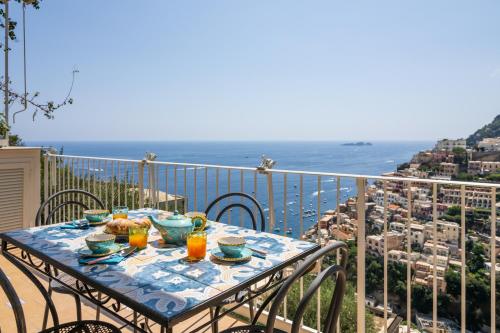 a table on a balcony with a view of the ocean at Casa Vittorina - De Vivo Realty Positano in Positano