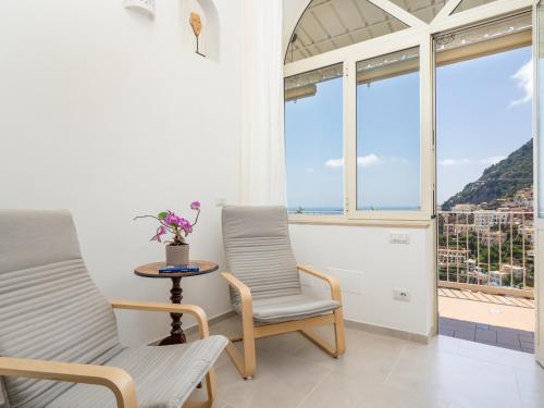 a room with two chairs and a table and windows at Casa Vittorina - De Vivo Realty Positano in Positano