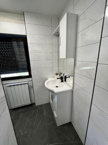 a white bathroom with a sink and a mirror at Charming flat in Maribor